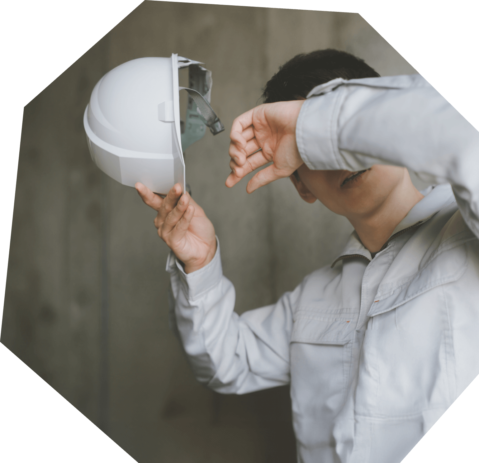 ヘルメットを手に持ち、汗を拭う男性作業員